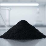 A macro shot of a mound of fine black iron oxide for paint, a deep matte powder, displayed in a clean industrial lab setting with glassware in the background.