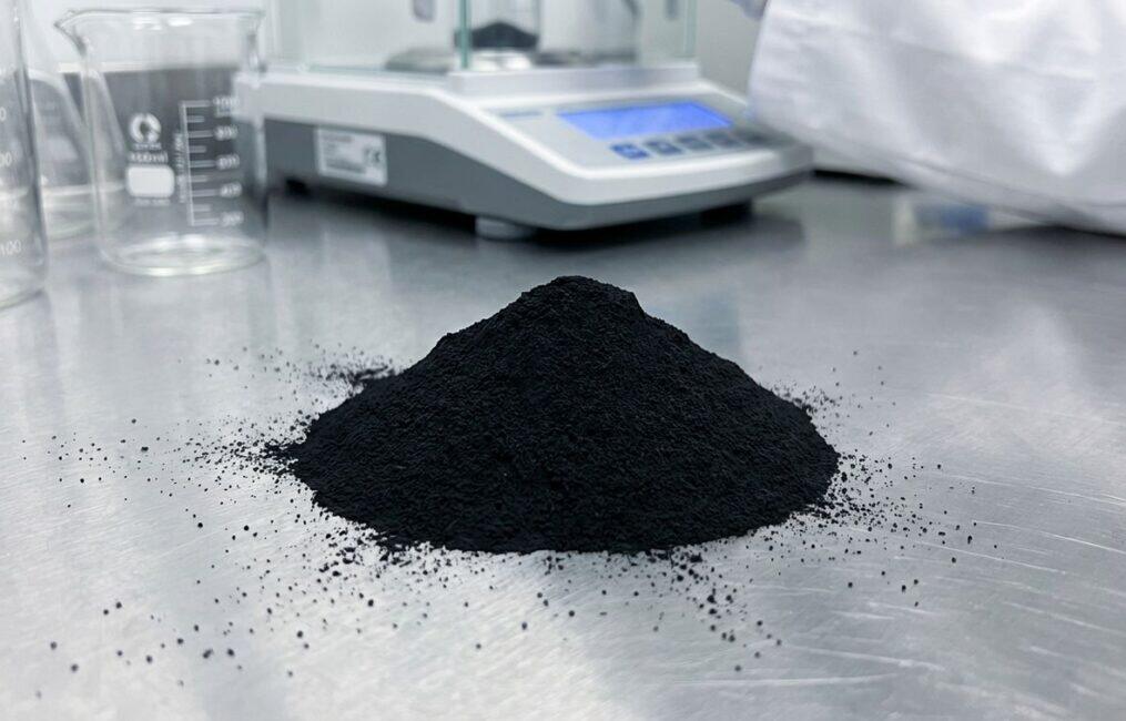 A macro shot of a mound of fine iron oxide black pigment for concrete, displayed in a clean lab setting to show its high purity and quality.