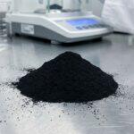 A macro shot of a mound of fine iron oxide black pigment for concrete, displayed in a clean lab setting to show its high purity and quality.