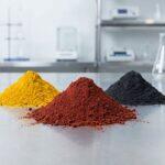 Three mounds of industrial-grade red, yellow, and black iron oxide powder in a lab, illustrating where to buy red iron oxide powder for manufacturing.